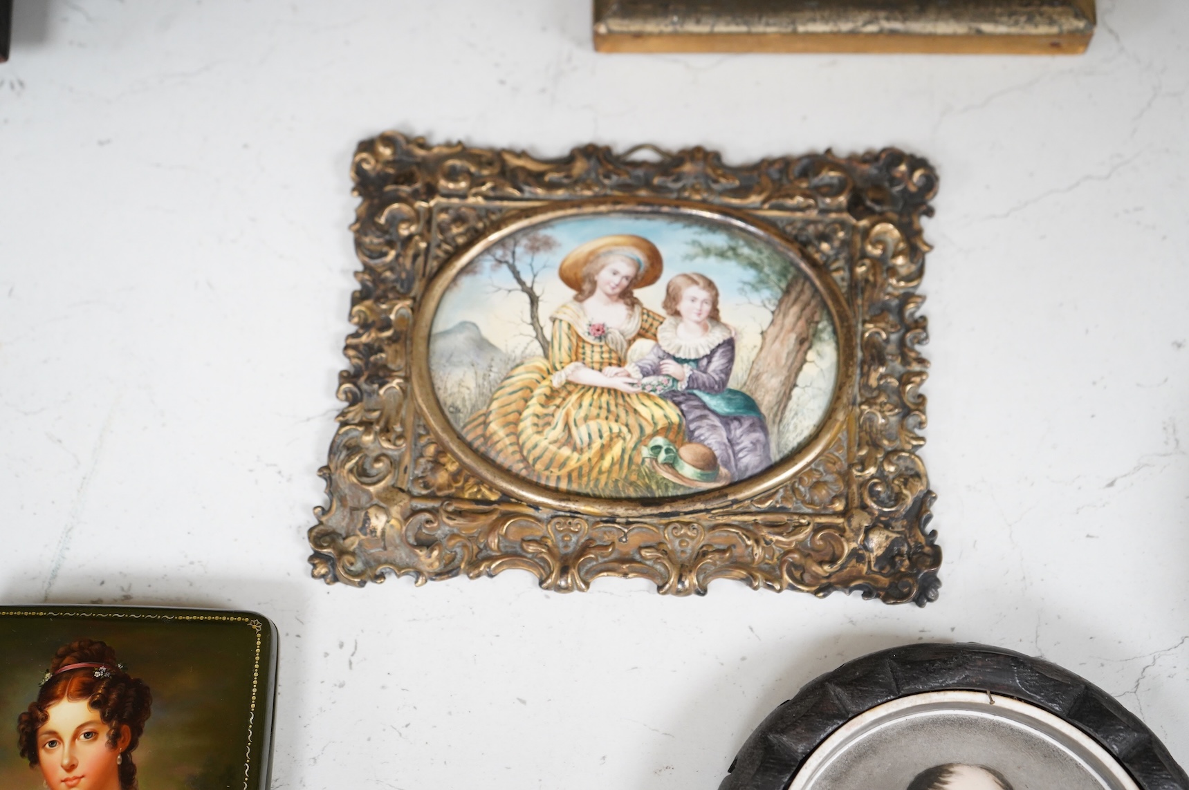 A collection of 19th century porcelain panels, pot lids and plaques to include a pair of hand painted floral lids, Russian lacquered box depicting a lady and a late 19th century Continental brass framed convex oval ename